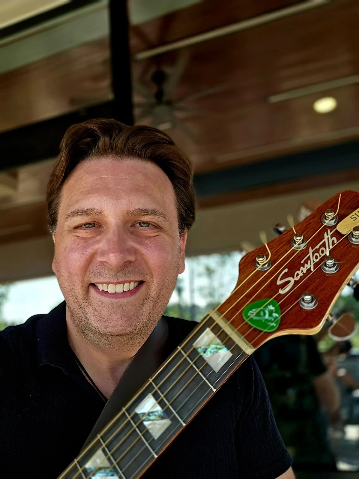 Dan Ennis smiling with his guitar