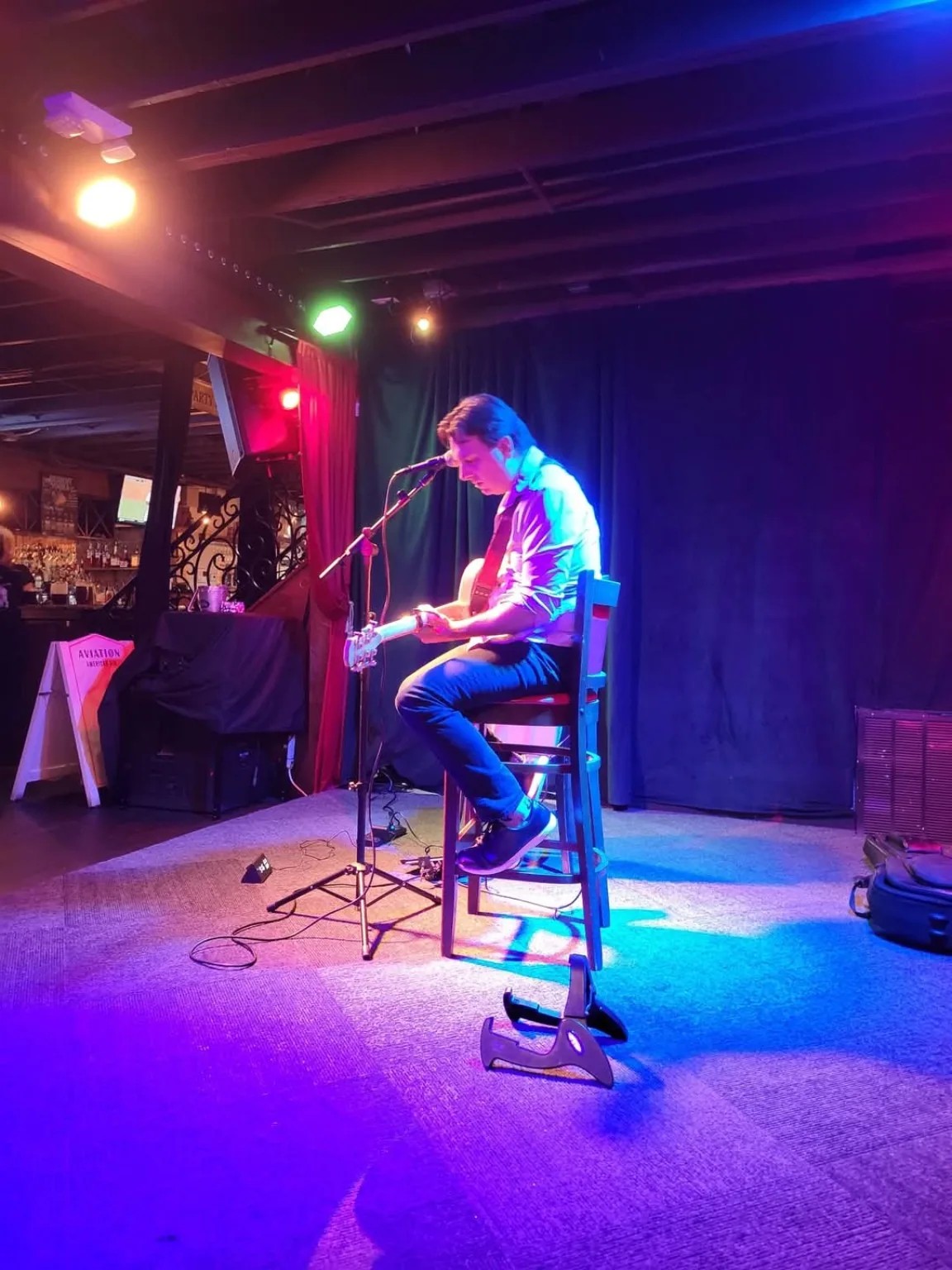 Dan Ennis playing guitar on a stage with colorful lighting